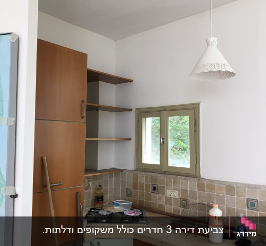 מטבח עם ארונות, כיור, כיריים ומנורה תלויה
